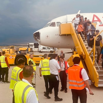 Another shot of the jet on the tarmac, showing a side angle on the damaged nose and passengers exiting via a staircase