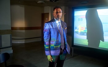 Siva Anandaciva of the King's Fund poses with a photograph of a hospital