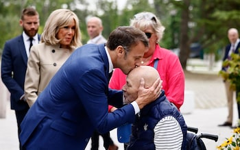 Emmanuel Macron kisses an elderly person's head as he and his wife Brigitte arrive at a polling station to cast their vote 