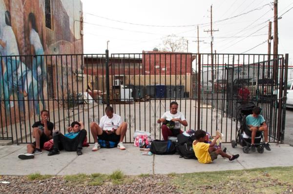 Migrants on the sidewalk outside of an overnight shelter at Sacred Heart Church in El Paso, Texas on August 8, 2023.