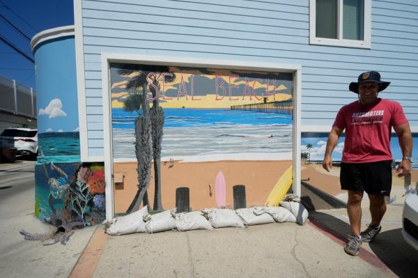 Cal Fire Firefighter-Paramedic Capt. Tyler Williams checks the sandbags set outside of his garage in Seal Beach, Calif. Hurricane Hilary is churning off Mexico's Pacific coast and heading into Southern California as the first tropical storm there in 84 years.
