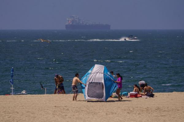 Beach goers hold o<em></em>nto their tent in California as the state anticipates its first tropical storm in nearly a century. 