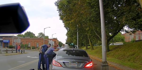 Two officers looking into Derek Lobo's car. 