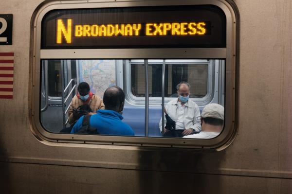 Riders seen through an N train window.