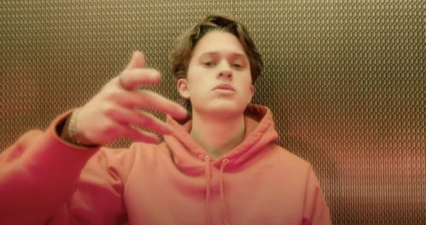 Deacon Phillippe sings in an orange hoodie.