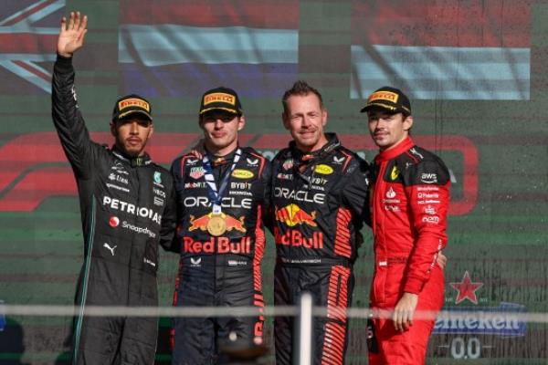 Lewis Hamilton salutes the crowd as he joins race winner Max Verstappen, Red Bull engineer Richard Wolverson and Charles Leclerc on the podium in Mexico