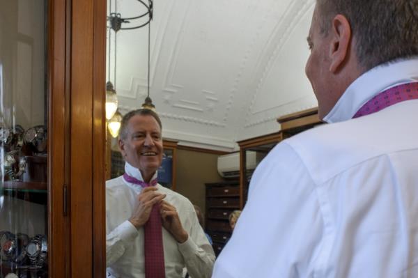 Bill de Blasio ties a tie while looking in the mirror. 