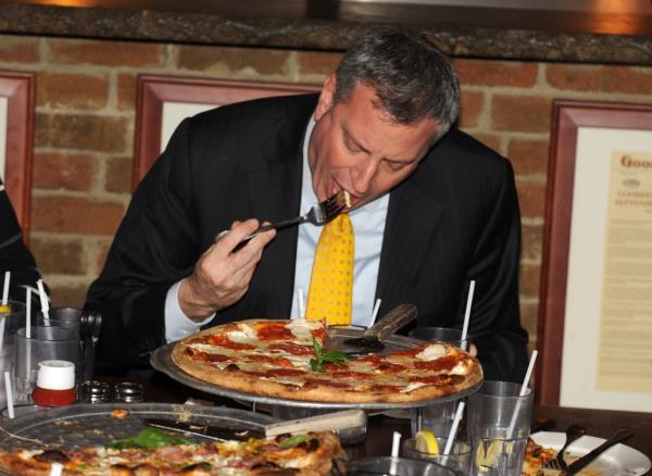 Bill de Blasio eating pizza with a fork.