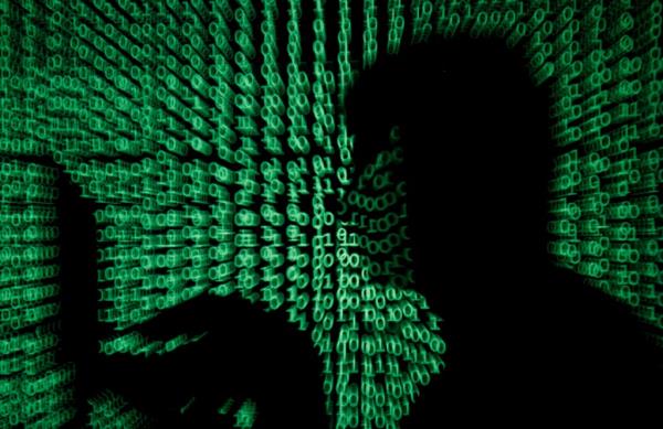 A man holds a laptop computer as cyber code is projected on him in this illustration.