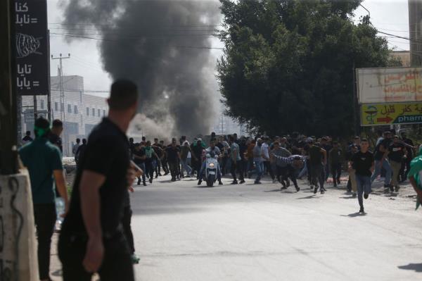 Palestinian protesters stand near black smoke rising during clashes with Israeli forces in the West Bank on Friday.