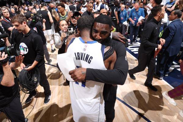 Mavericks assistant God Shammgod hugs Kyrie Irving after Dallas' Game 3 win over the Timberwolves in the Western Co<em></em>nference Finals.