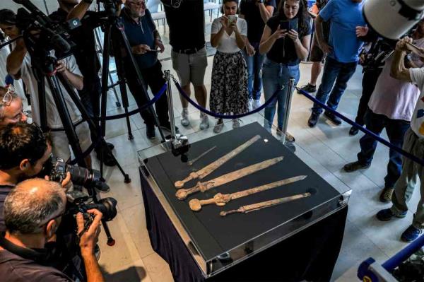 Journalists gather around a showcase displaying a shafted pilum (javelin) and four swords dating a<em></em>bout 1,900-years-old swords, preserved in their wooden and leather scabbards, found in a Judean Desert cave, presented by researchers from the Israel Antiquities Authority (IAA) and Ariel University at a press co<em></em>nference at the Jay and Jeanie Schottenstein Natio<em></em>nal campus for the Archeology of Israel in Jerusalem on September 6, 2023. 