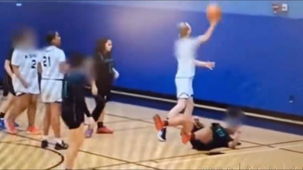 The bearded trans basketball player and the injured female oppo<em></em>nent on the ground.