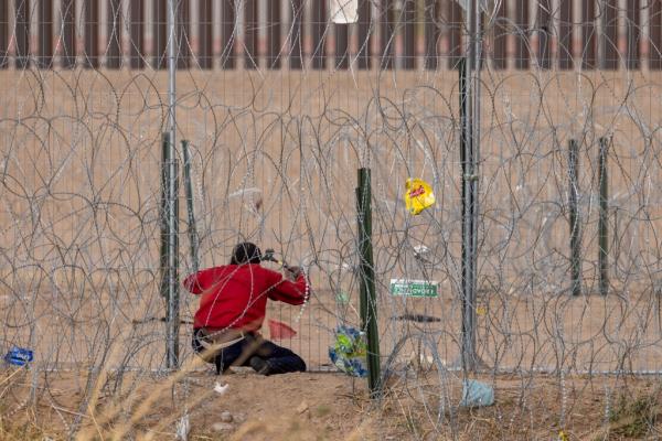 A migrant uses bolt cutters to cut Texas border wire near El Paso