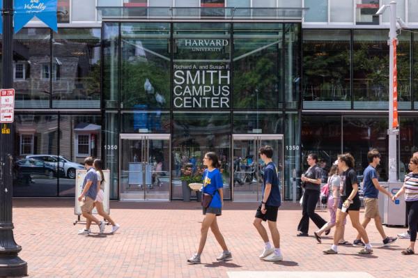 People walking past glass building, Harvard Campus Center, Cambridge, Massachusetts.