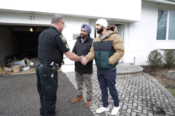 The Chawlas greet a member of the Nassau County Sheriff's Office with a handshake in the driveway of the Friendly Lane home this week after authorities officially evicted the accused squatters.