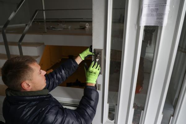 a worker in green plastic gloves changes lock on the Friendly Lane home.