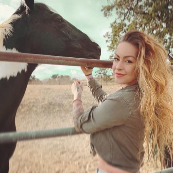 Anita Joy standing next to a horse, remembering her late friend, actor Johnny Wactor