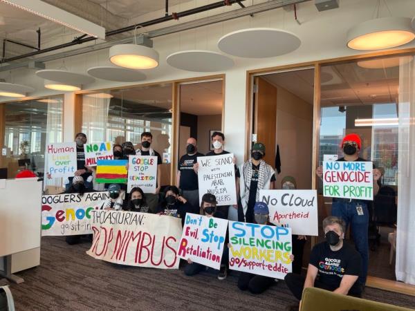 A large group of Google employees hold signs protesting their company's participation in 
