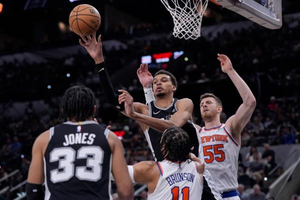 San Anto<em></em>nio Spurs center Victor Wembanyama, center, passes the ball over New York Knicks guard Jalen Brunson (11) during the second half of an NBA basketball game in San Antonio, Friday, March 29, 2024.