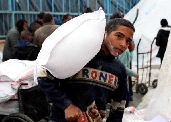 A Palestinian boy carries a bag of flour distributed by the United Nations Relief and Works Agency (UNRWA), amid the o<em></em>ngoing co<em></em>nflict between Israel and Hamas, in Rafah in the southern Gaza Strip January 29, 2024.