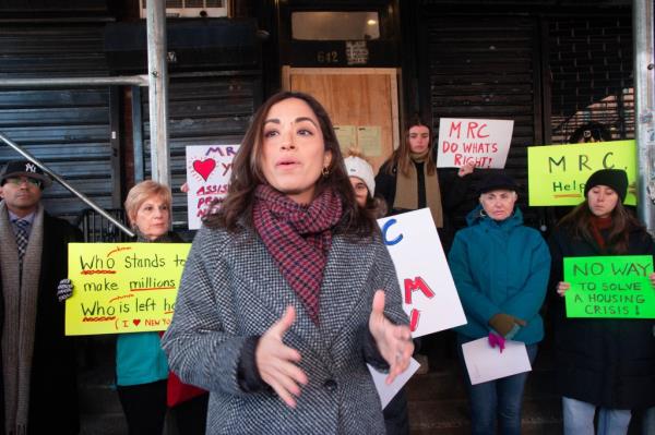 Carlina Rivera speaking publicly while community members stand behind her