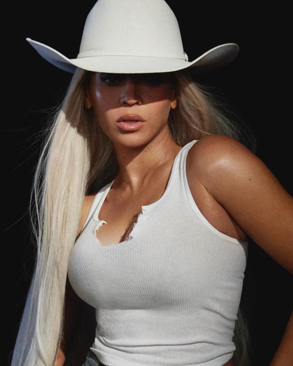 Beyoncé posing in a ripped white tank top and cowboy hat