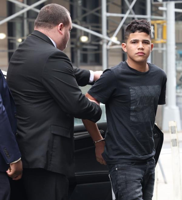 A man in a suit holding a young man's hand being brought to Criminal Court in Manhattan, NY.