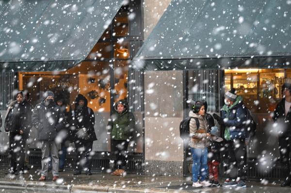 Commuters wait for a transit bus at the intersection of Milwaukee Avenue, Damen Avenue and North Avenue as it snows on Tuesday, January 9, 2024 in Chicago, Illinois