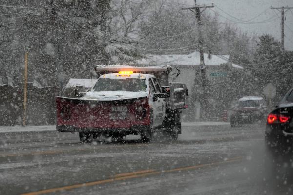 A snow plow drives on an ice-covered road in Illinois