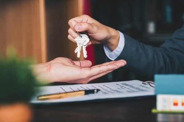 Keys getting handed over to buyer/renter with paperwork/application materials seen.
