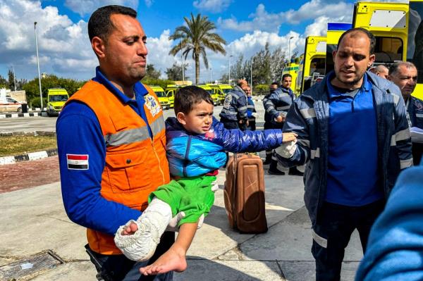 An injured Palestinian child is carried by an Egyptian Red Crescent paramedic after evacuation from the Gaza Strip via Rafah on Saturday.