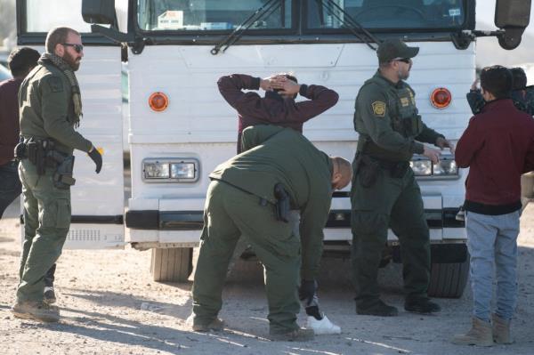 Migrants are body searched before boarding a bus at the temporary processing center after crossing the border wall into the U.S. from Mexico, as the number of migrants surges in the border town of Lukeville, Arizona, U.S. December 12, 2023.