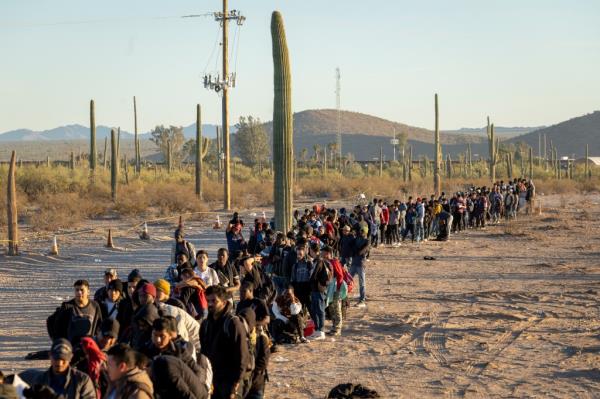 Immigrants line up at a remote U.S. Border Patrol processing center after crossing the U.S.-Mexico border on December 07, 2023 in Lukeville, Arizona. 