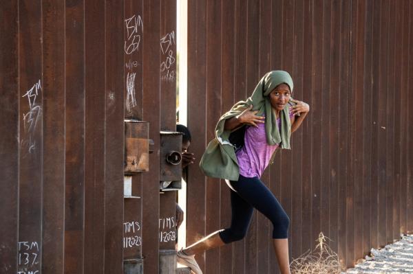 A migrant crosses the border wall through a gap into the U.S. from Mexico, as the number of migrants surges in the border town of Lukeville, Arizona, U.S. December 12, 2023.