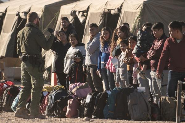 Migrants wait to be processed and transported at the temporary processing center after crossing the border wall into the U.S. from Mexico, as the number of migrants surges in the border town of Lukeville, Arizona, U.S. December 12, 2023.  