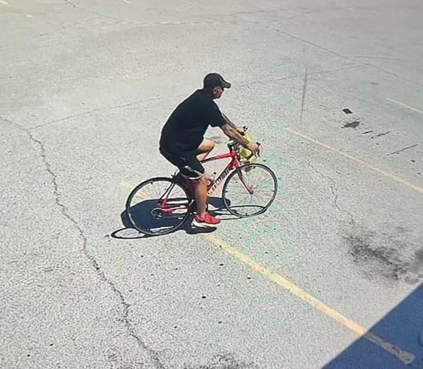 A man in black clothing riding a red bicycle