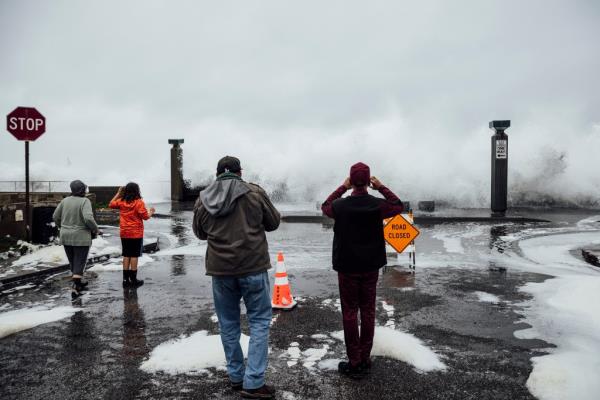 People watch the waves near Pacifica Municipal Pier in Pacifica, Calif., on Dec. 28, 2023.