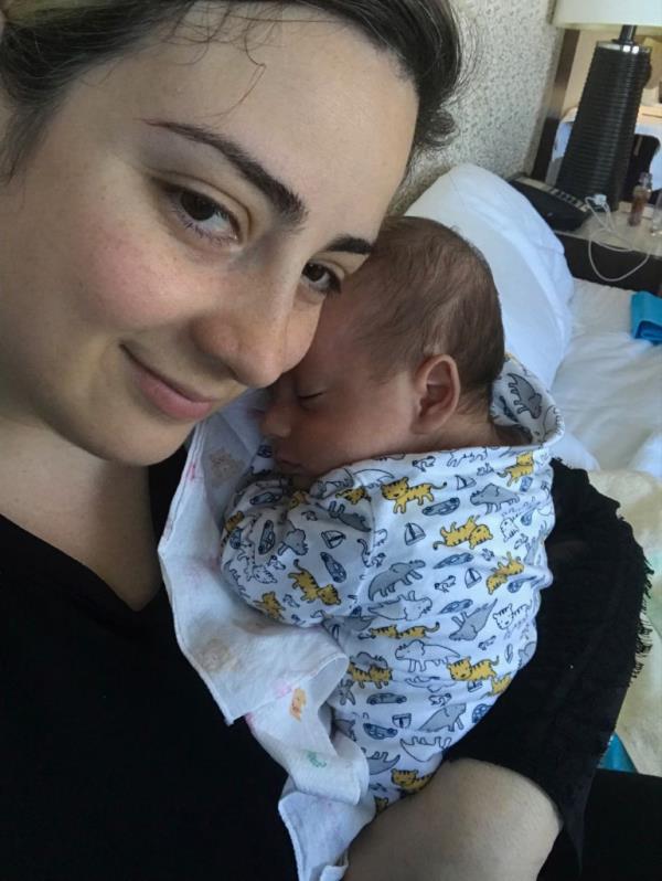 anni manukyan holding her sleeping infant on her shoulder.