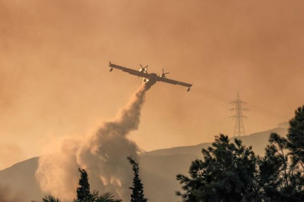 A firefighting plane makes a water drop