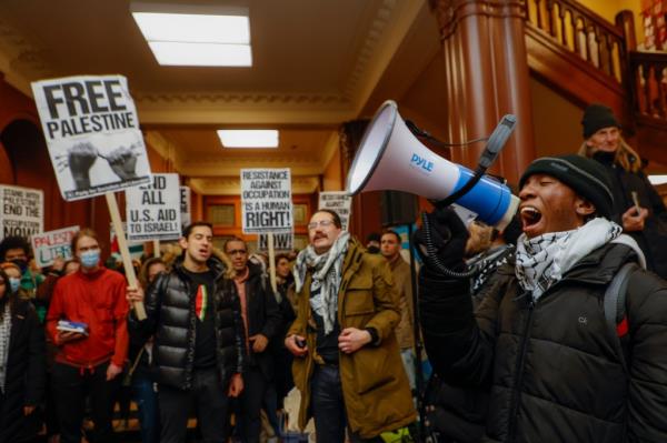 Kojo Acheampong, a Harvard student and member of AFRO (African and African American Resistance Organization), speaks to Pro-Palestine supporters in the lobby of Cambridge City Hall before their scheduled meeting.