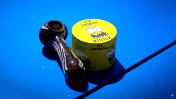 A photo of a marijuana pipe and a tin saying 