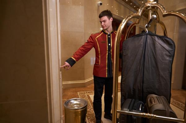 Bell hop pressing an elevator button