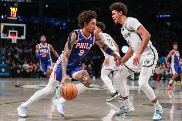 Cam Johnson defends Kelly Oubre before suffering a right ankle sprain in the Nets' win over the 76ers.