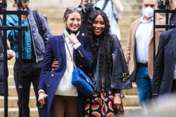 Naomi Campbell wearing a black leather biker jacket, a blue and red dress with printed patterns, black pants; Christy Turlington wears sunglasses, a white turtleneck oversized wool knitted pullover, a navy blue military long coat with buttons, a blue quilted Chanel bag, brown flared pants, after the Fendi show during Paris Fashion Week - Haute Couture Spring/Summer 2021 in Paris, France.