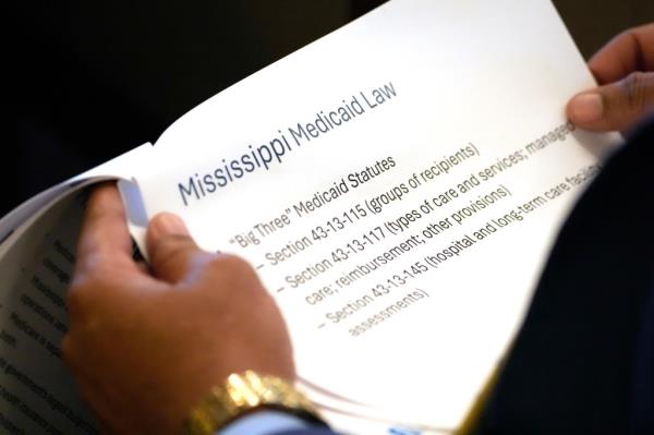 A person holding a docu<em></em>ment a<em></em>bout Mississippi Medicaid provided to the House Medicaid Committee at the Mississippi Capitol.