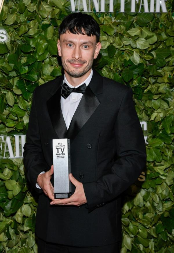 Richard Gadd with Gotham TV award, standing in front of greenery