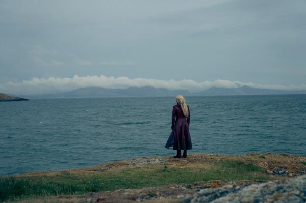 A person with her back to the camera looking at the sea. 