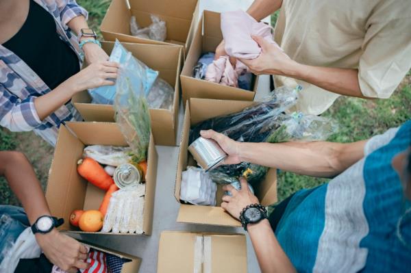 A group of young Asian volunteers preparing grocery food into boxes for those needy people havin<em></em>g financial difficulty during global eco<em></em>nomy crisis. Food box filled with fresh vegetables, fruits, cereals, milk, eggs and canned goods are deliver to the local needy community during a outdoor food drive.