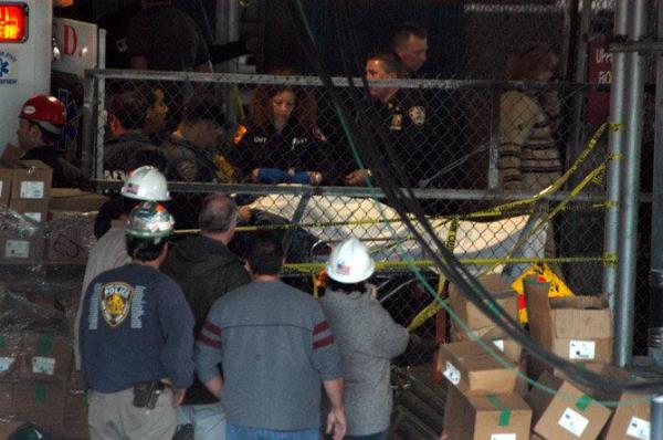 A victim is brought out from the Staten island Ferry barberi as co<em></em>nstruction workers look on. 